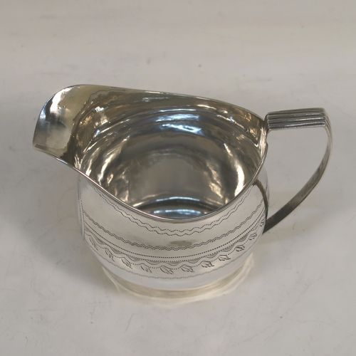 A very pretty Antique Georgian Sterling Silver cream jug, having a round bellied body with hand-engraved bands of stipple and floral work, an applied reeded border and reeded scroll handle, and all sitting on a flat base. This elegant antique silver cream jug was made by Urquart and Hart of London in 1786. The dimensions of this fine hand-made antique silver cream jug are height  cms (3.75 inches), length 11 cms (4.3 inches), and it weighs approx. 78g (2.5 troy ounces).   