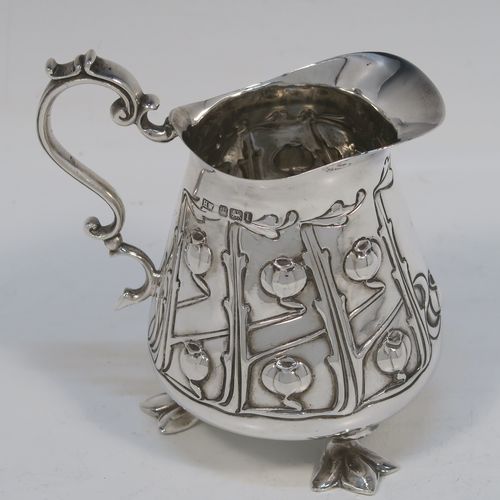 A very pretty Arts and Crafts Antique Edwardian Sterling Silver cream or milk jug having a round bellied body with hand-chased poppy seed head and leaf floral decoration, a cast scroll side-handle, and sitting on three cast trefoil feet. This beautiful Arts and Crafts style silver milk jug was made by Lee and Wigfull (Henry Wigfull) of Sheffield in 1903. The dimensions of this fine hand-made antique silver cream jug are height 9 cms (3.5 inches), length 9 cms (3.5 inches), and it weighs approx. 114g (3.7 troy ounces).   