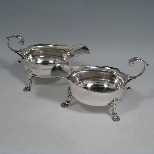 A very handsome Antique Georgian George II Sterling Silver pair of cream boats, having plain bellied bodies, with Chippendale style top borders, cast flying scroll side handles, and sitting on three cast hoof feet with shell shoulders. This beautiful pair of antique silver cream boats were made by Walter Brind of London in 1751. The dimensions of these fine hand-made antique silver cream boats are length 13.5 cms (5.25 inches), height 8 cms (3 inches), and they weigh a total of approx. 225g (7.3 troy ounces).