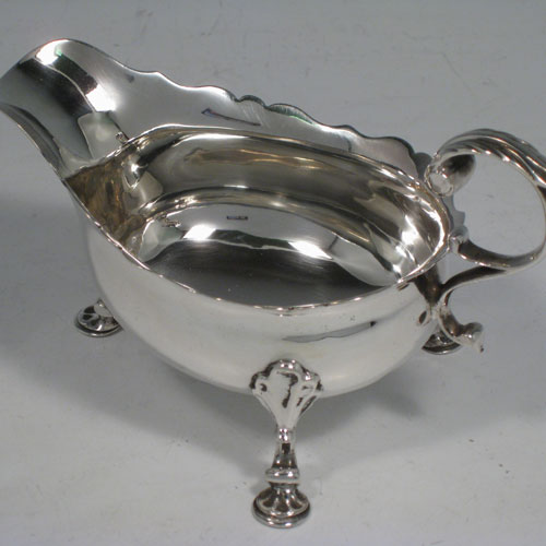 A very handsome Antique Georgian George II Sterling Silver pair of cream boats, having plain bellied bodies, with Chippendale style top borders, cast flying scroll side handles, and sitting on three cast hoof feet with shell shoulders. This beautiful pair of antique silver cream boats were made by Walter Brind of London in 1751. The dimensions of these fine hand-made antique silver cream boats are length 13.5 cms (5.25 inches), height 8 cms (3 inches), and they weigh a total of approx. 225g (7.3 troy ounces).