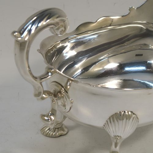 A very handsome Antique Georgian Sterling Silver George II sauce or gravy boat, having a plain bellied body, with a Chippendale border, a cast scroll handle, and sitting on three cast and fluted hoof feet. This beautiful antique silver sauce boat was made by Robert Tyrill (poss.) of London in 1755. The dimensions of this fine hand-made antique silver sauce boat are length 18.5 cms (7.25 inches), width 10 cms (4 inches), height 12 cms (4.75 inches), and it weighs 327g (10.5 troy ounces). Please note that this item is crested on one side.