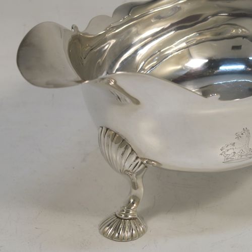 A very handsome Antique Georgian Sterling Silver George II sauce or gravy boat, having a plain bellied body, with a Chippendale border, a cast scroll handle, and sitting on three cast and fluted hoof feet. This beautiful antique silver sauce boat was made by Robert Tyrill (poss.) of London in 1755. The dimensions of this fine hand-made antique silver sauce boat are length 18.5 cms (7.25 inches), width 10 cms (4 inches), height 12 cms (4.75 inches), and it weighs 327g (10.5 troy ounces). Please note that this item is crested on one side.