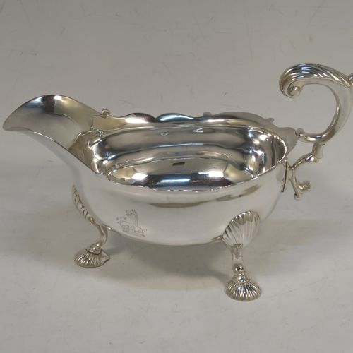 A very handsome Antique Georgian Sterling Silver George II sauce or gravy boat, having a plain bellied body, with a Chippendale border, a cast scroll handle, and sitting on three cast and fluted hoof feet. This beautiful antique silver sauce boat was made by Robert Tyrill (poss.) of London in 1755. The dimensions of this fine hand-made antique silver sauce boat are length 18.5 cms (7.25 inches), width 10 cms (4 inches), height 12 cms (4.75 inches), and it weighs 327g (10.5 troy ounces). Please note that this item is crested on one side.