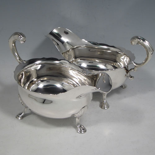 Antique Georgian sterling silver pair of large sauce or gravy boats, having plain baluster bodies, Chippendale borders, cast scroll handles, and sitting on three cast hoof feet with shell shoulders. Made by Thomas Cooke II and Richard Gurney of London in 1753. The dimensions of these fine hand-made antique silver sauce boats are length 18 cms (7 inches), width 10 cms (4 inches), height 11.5 cms (4.5 inches), and they weigh a total of 495g (16 troy ounces).