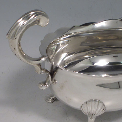 Antique Georgian sterling silver pair of large sauce or gravy boats, having plain baluster bodies, Chippendale borders, cast scroll handles, and sitting on three cast hoof feet with shell shoulders. Made by Thomas Cooke II and Richard Gurney of London in 1753. The dimensions of these fine hand-made antique silver sauce boats are length 18 cms (7 inches), width 10 cms (4 inches), height 11.5 cms (4.5 inches), and they weigh a total of 495g (16 troy ounces).