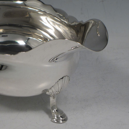 Antique Georgian sterling silver pair of large sauce or gravy boats, having plain baluster bodies, Chippendale borders, cast scroll handles, and sitting on three cast hoof feet with shell shoulders. Made by Thomas Cooke II and Richard Gurney of London in 1753. The dimensions of these fine hand-made antique silver sauce boats are length 18 cms (7 inches), width 10 cms (4 inches), height 11.5 cms (4.5 inches), and they weigh a total of 495g (16 troy ounces).