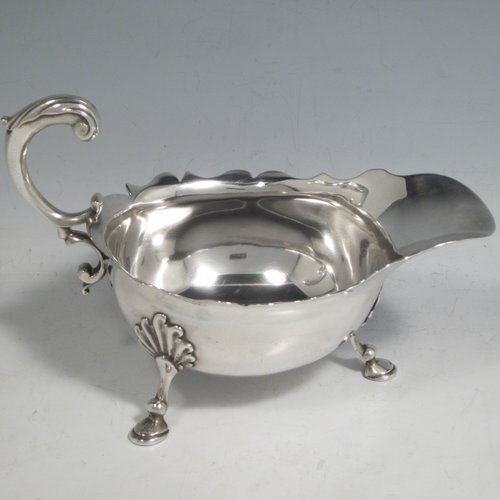 A handsome Antique Georgian sterling silver George II sauce or gravy boat, having a plain baluster body, with a Chippendale border, cast scroll handle, and sitting on three cast hoof feet with shell shoulders. This elegant antique silver sauce boat was made by Robert Albin Cox (poss.) of London in 1753. The dimensions of this fine hand-made antique silver sauce boat are length 19 cms (7.5 inches), width 8.3 cms (3.3 inches), height 11 cms (4.25 inches), and it weighs 264g (8.5 troy ounces).   