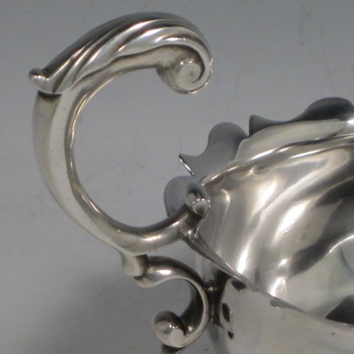 A handsome Antique Georgian sterling silver George II sauce or gravy boat, having a plain baluster body, with a Chippendale border, cast scroll handle, and sitting on three cast hoof feet with shell shoulders. This elegant antique silver sauce boat was made by Robert Albin Cox (poss.) of London in 1753. The dimensions of this fine hand-made antique silver sauce boat are length 19 cms (7.5 inches), width 8.3 cms (3.3 inches), height 11 cms (4.25 inches), and it weighs 264g (8.5 troy ounces).   