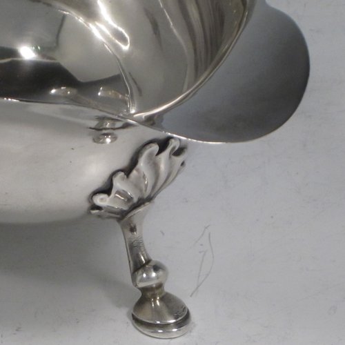 A handsome Antique Georgian sterling silver George II sauce or gravy boat, having a plain baluster body, with a Chippendale border, cast scroll handle, and sitting on three cast hoof feet with shell shoulders. This elegant antique silver sauce boat was made by Robert Albin Cox (poss.) of London in 1753. The dimensions of this fine hand-made antique silver sauce boat are length 19 cms (7.5 inches), width 8.3 cms (3.3 inches), height 11 cms (4.25 inches), and it weighs 264g (8.5 troy ounces).   