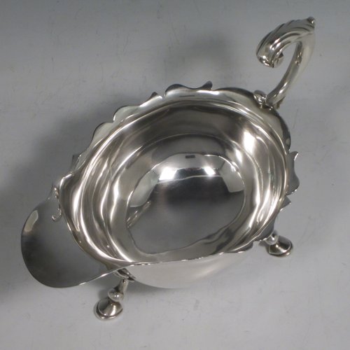 A handsome Antique Georgian sterling silver George II sauce or gravy boat, having a plain baluster body, with a Chippendale border, cast scroll handle, and sitting on three cast hoof feet with shell shoulders. This elegant antique silver sauce boat was made by Robert Albin Cox (poss.) of London in 1753. The dimensions of this fine hand-made antique silver sauce boat are length 19 cms (7.5 inches), width 8.3 cms (3.3 inches), height 11 cms (4.25 inches), and it weighs 264g (8.5 troy ounces).   