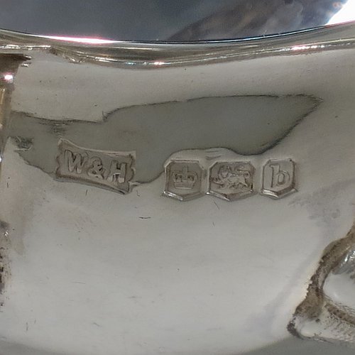 A handsome Antique Sterling Silver pair of sauce boats or gravy boats, having plain bellied bodies, with Chippendale borders, cast flying scroll handles with anthemion leaf thumb-pieces, and sitting on three cast hoof feet with shell shoulders. These elegant silver sauce boats were made by Walker & Hall of Sheffield in 1919. The dimensions of these fine hand-made antique silver gravy or sauce boats are length 15 cms (6 inches), width 9 cms (3.5 inches), height 9 cms (3.5 inches), and they weigh a total of approx. 390g (12.6 troy ounces).    