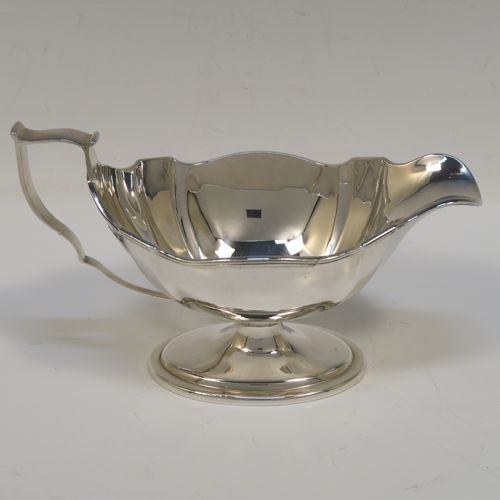 An elegant Antique Edwardian Sterling Silver pair of sauce boats, having plain shaped oval bellied bodies, with applied reeded borders, cast scroll side-handles, and sitting on pedestal feet. This handsome pair of silver sauce boats were made by Thomas Bradbury of Sheffield in 1910. The dimensions of this fine pair of hand-made antique sauce boats are length 18 cms (7 inches), height 10 cms (4 inches), width 8.5 cms (3.3 inches), and they weigh a total of approx. 497g (16 troy ounces).   