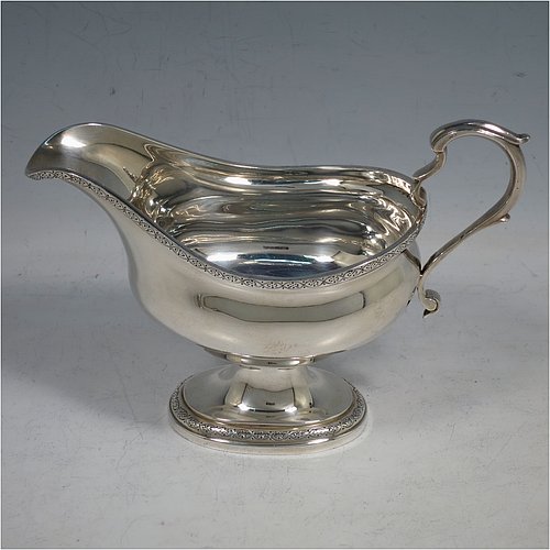 A Sterling Silver pair of sauce boats, having plain oval bellied bodies, with applied floral borders, cast scroll handles, and sitting on pedestal feet. Made by J. Parkes & Co., of London in 1938. The dimensions of this fine pair of hand-made sauce boats are length 16 cms (6.3 inches), height 11.5 cms (4.5 inches), width 8 cms (3 inches), and they weigh a total of approx. 422g (13.6 troy ounces).