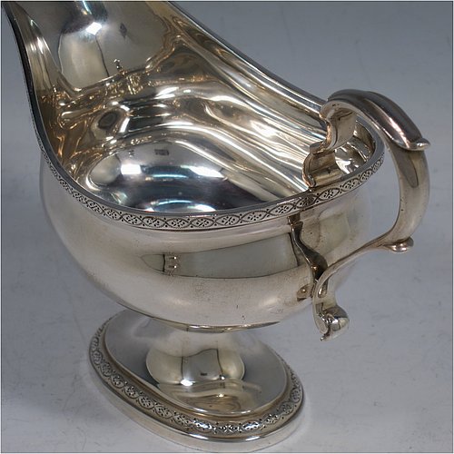 A Sterling Silver pair of sauce boats, having plain oval bellied bodies, with applied floral borders, cast scroll handles, and sitting on pedestal feet. Made by J. Parkes & Co., of London in 1938. The dimensions of this fine pair of hand-made sauce boats are length 16 cms (6.3 inches), height 11.5 cms (4.5 inches), width 8 cms (3 inches), and they weigh a total of approx. 422g (13.6 troy ounces).