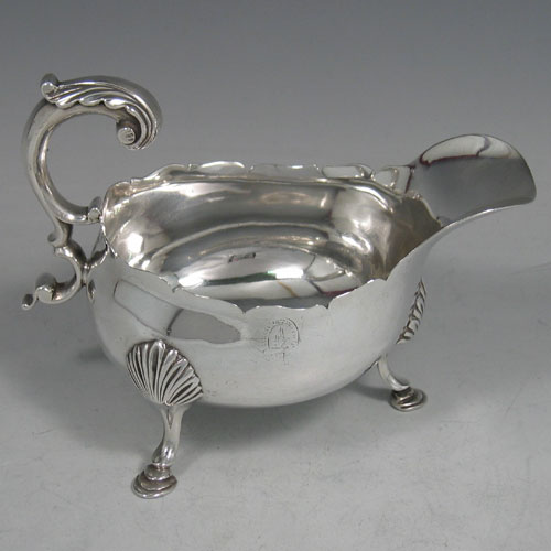 Antique Georgian sterling silver pair of sauce or gravy boats, having plain baluster bodies, chippendale borders, cast scoll handles, and sitting on three cast hoof feet with shell shoulders. Made by William Shaw II of London in 1765. The dimensions of these fine hand-made pair of antique silver sauce boats are length 16 cms (6.25 inches), width 10 cms (4 inches), height 11.5 cms (4.5 inches), and they weigh a total of 568g (18.3 troy ounces). Please note that these are crested.