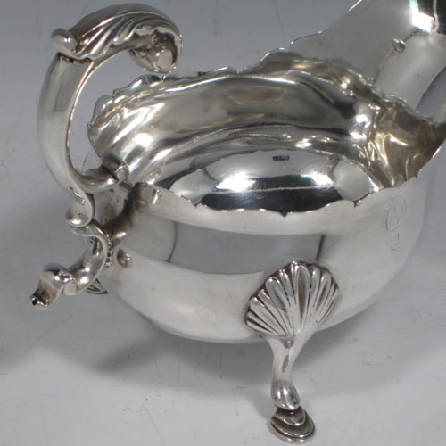 Antique Georgian sterling silver pair of sauce or gravy boats, having plain baluster bodies, chippendale borders, cast scoll handles, and sitting on three cast hoof feet with shell shoulders. Made by William Shaw II of London in 1765. The dimensions of these fine hand-made pair of antique silver sauce boats are length 16 cms (6.25 inches), width 10 cms (4 inches), height 11.5 cms (4.5 inches), and they weigh a total of 568g (18.3 troy ounces). Please note that these are crested.