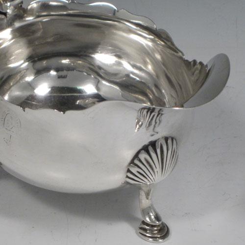 Antique Georgian sterling silver pair of sauce or gravy boats, having plain baluster bodies, chippendale borders, cast scoll handles, and sitting on three cast hoof feet with shell shoulders. Made by William Shaw II of London in 1765. The dimensions of these fine hand-made pair of antique silver sauce boats are length 16 cms (6.25 inches), width 10 cms (4 inches), height 11.5 cms (4.5 inches), and they weigh a total of 568g (18.3 troy ounces). Please note that these are crested.