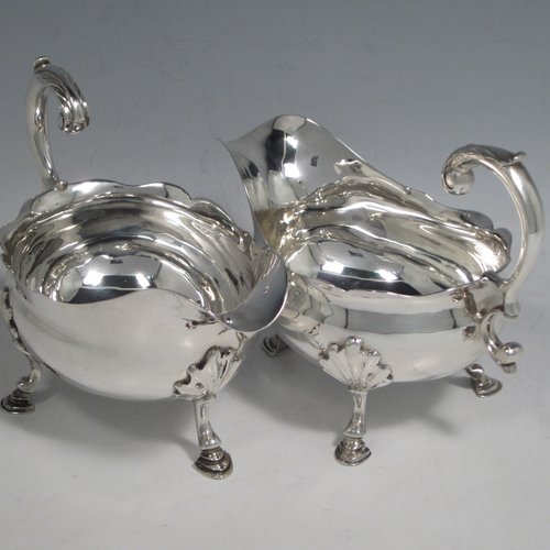 Antique Georgian sterling silver pair of sauce or gravy boats, having plain baluster bodies, Chippendale borders, cast scroll handles, and sitting on three cast hoof feet with shell shoulders. Made by William Smith I of London in 1761. The dimensions of these fine hand-made antique silver sauce boats are length 15 cms (6 inches), width 8.3 cms (3.3 inches), height 11.5 cms (4.5 inches), and they weigh a total of 405g (13 troy ounces).  