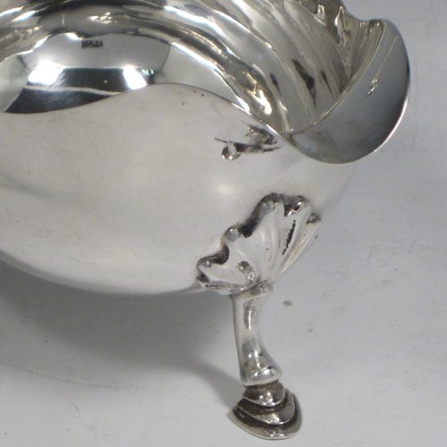 Antique Georgian sterling silver pair of sauce or gravy boats, having plain baluster bodies, Chippendale borders, cast scroll handles, and sitting on three cast hoof feet with shell shoulders. Made by William Smith I of London in 1761. The dimensions of these fine hand-made antique silver sauce boats are length 15 cms (6 inches), width 8.3 cms (3.3 inches), height 11.5 cms (4.5 inches), and they weigh a total of 405g (13 troy ounces).  