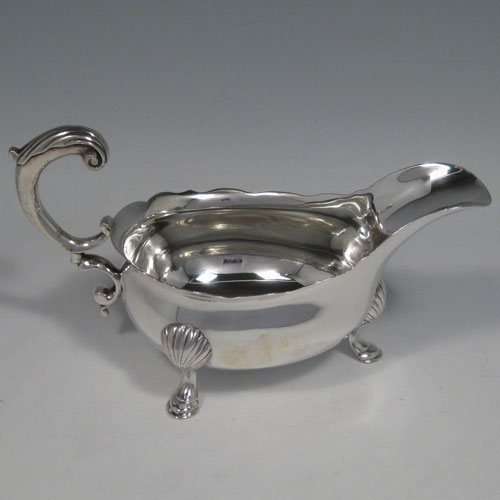 A handsome Antique Georgian Sterling Silver sauce boat, having a plain bellied body, with a Chippendale top border, a cast scroll handle, and sitting on three cast hoof feet with fluted shoulders. This beautiful antique silver sauce boat was made by George Rous of London in 1755. The dimensions of this fine hand-made antique silver sauce boat are length 18 cms (7 inches), height 9 cms (3.5 inches), width 8.5 cms (3.25 inches), and it weighs approx. 209g (6.7 troy ounces).