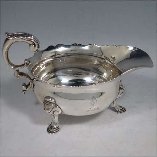 An Antique Georgian Sterling Silver George II sauce or gravy boat, having a plain baluster body, with a Chippendale border, cast scroll handle, and sitting on three cast hoof feet with scroll shoulders. Made in London in 1746. The dimensions of this fine hand-made antique silver sauce boat are length 16.5 cms (6.5 inches), width 10 cms (4 inches), height 10 cms (4 inches), and it weighs 280g (9 troy ounces). Please note that this item is crested.