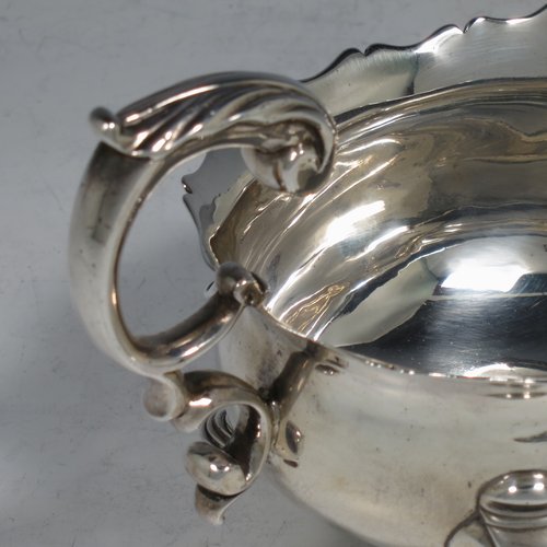 An Antique Georgian Sterling Silver George II sauce or gravy boat, having a plain baluster body, with a Chippendale border, cast scroll handle, and sitting on three cast hoof feet with scroll shoulders. Made in London in 1746. The dimensions of this fine hand-made antique silver sauce boat are length 16.5 cms (6.5 inches), width 10 cms (4 inches), height 10 cms (4 inches), and it weighs 280g (9 troy ounces). Please note that this item is crested.