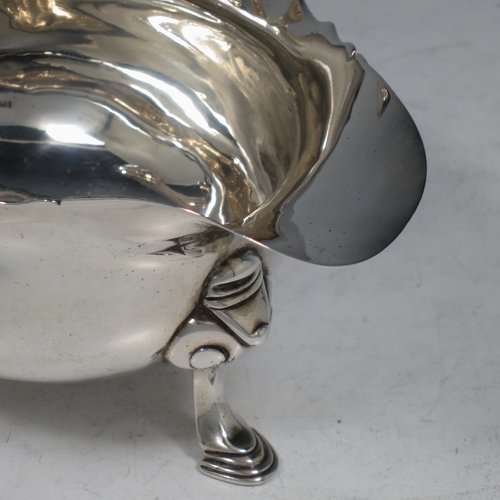 An Antique Georgian Sterling Silver George II sauce or gravy boat, having a plain baluster body, with a Chippendale border, cast scroll handle, and sitting on three cast hoof feet with scroll shoulders. Made in London in 1746. The dimensions of this fine hand-made antique silver sauce boat are length 16.5 cms (6.5 inches), width 10 cms (4 inches), height 10 cms (4 inches), and it weighs 280g (9 troy ounces). Please note that this item is crested.