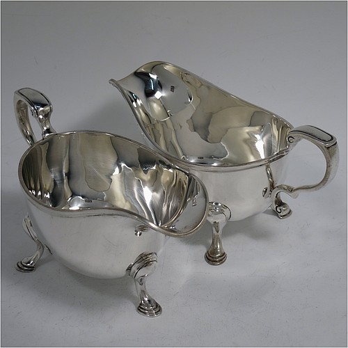 A very handsome Sterling Silver pair of sauce boats or gravy boats in a Georgian style, having plain bellied bodies, with applied Reeded borders, cast scroll handles, and sitting on three cast hoof feet. Made by Wakely & Wheeler of London in 1933. The dimensions of these fine hand-made silver gravy or sauce boats are length 16 cms (6.25 inches), width 8 cms (3 inches), height 8 cms (3.25 inches), and they weigh a total of approx. 381g (12.3 troy ounces).    