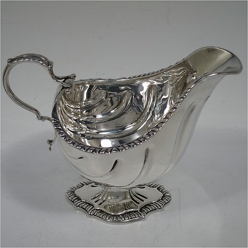 A very handsome Antique Edwardian Sterling Silver pair of sauce boats or gravy boats in a Georgian George II style, having bellied bodies with hand-chased swirl fluting, with applied gadroon borders, cast scroll handles with anthemion leaf tops, and sitting on shaped oval pedestal feet. Made by D & J Welby of London in 1904. The dimensions of these fine hand-made antique silver gravy or sauce boats are length 16.5 cms (6.5 inches), width 10 cms (4 inches), height 11.5 cms (4.5 inches), and they weigh a total of approx. 480g (15.5 troy ounces).   