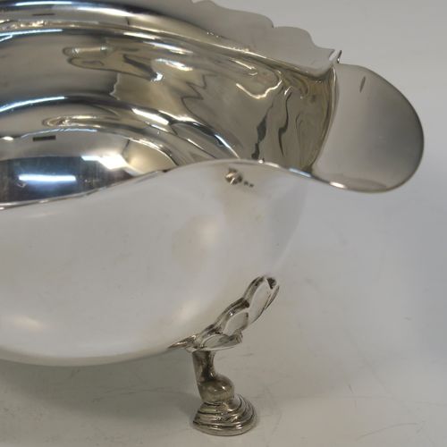 A handsome Sterling Silver pair of sauce boats or gravy boats, having plain bellied bodies, with Chippendale borders, cast flying scroll handles with anthemion leaf thumb-pieces, and sitting on three cast hoof feet with shell shoulders. These elegant silver sauce boats were made by Mappin and Webb of Sheffield in 1976. The dimensions of these fine hand-made silver gravy or sauce boats are length 19 cms (7.5 inches), width 11 cms (4.3 inches), height 12 cms (4.75 inches), and they weigh a total of approx. 534g (17.2 troy ounces).  