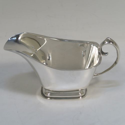 A stylish pair of Sterling Silver Irish cream or sauce boats in a Modernistic style, having plain bodies with tapering sides, scroll side-handles with thumb-pieces, and sitting on rectangular pedestal feet. These elegant silver sauce or cream boats were hallmarked for Dublin in 1965. The dimensions of this fine hand-made pair of silver cream or sauce boats are length 14 cms (5.5 inches), height 7.5 cms (3 inches), width 7 cms (2.75 inches), and with a total weight of approx. 223g (7.2 troy ounces).   