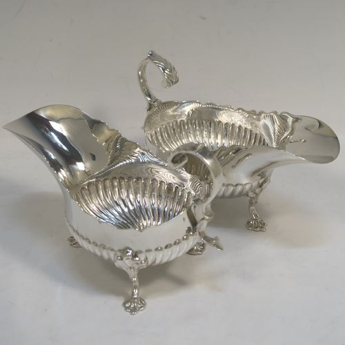 A very pretty pair of Antique Victorian Sterling Silver sauce or gravy boats, having hand-chased half-fluted decoration, with Chippendale top borders, cast scroll handles, and sitting on three cast floral feet. These beautiful antique silver sauce boats were made by John Henry Rawlings of London in 1890. The dimensions of these fine hand-made silver gravy or sauce boats are length 16.5 cms (6.5 inches), width 9 cms (3.5 inches), height 10 cms (4 inches), and they weigh a total of approx. 462g (15 troy ounces).   