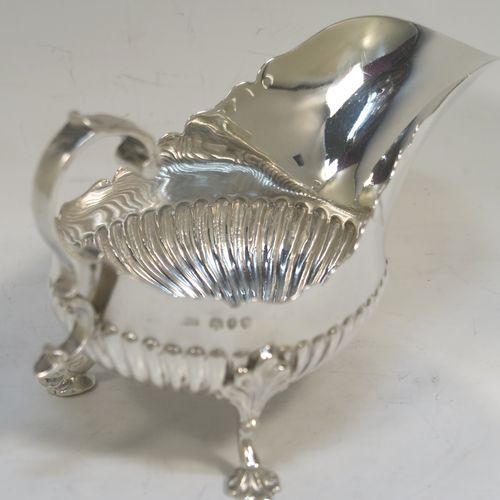 A very pretty pair of Antique Victorian Sterling Silver sauce or gravy boats, having hand-chased half-fluted decoration, with Chippendale top borders, cast scroll handles, and sitting on three cast floral feet. These beautiful antique silver sauce boats were made by John Henry Rawlings of London in 1890. The dimensions of these fine hand-made silver gravy or sauce boats are length 16.5 cms (6.5 inches), width 9 cms (3.5 inches), height 10 cms (4 inches), and they weigh a total of approx. 462g (15 troy ounces).   