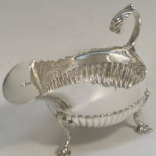 A very pretty pair of Antique Victorian Sterling Silver sauce or gravy boats, having hand-chased half-fluted decoration, with Chippendale top borders, cast scroll handles, and sitting on three cast floral feet. These beautiful antique silver sauce boats were made by John Henry Rawlings of London in 1890. The dimensions of these fine hand-made silver gravy or sauce boats are length 16.5 cms (6.5 inches), width 9 cms (3.5 inches), height 10 cms (4 inches), and they weigh a total of approx. 462g (15 troy ounces).   