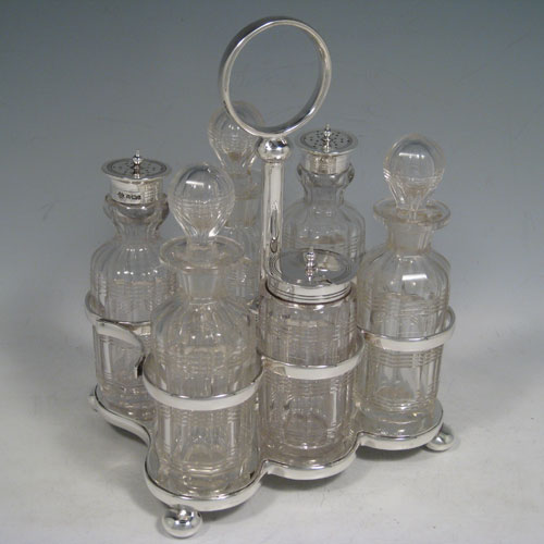 Antique Victorian sterling silver cruet set, having a plain stand with ring handle and frame for six hand-cut crystal cruet bottles with original stoppers and silver mounts, all sitting on a base with four cushion feet. Made by William Hutton and Sons of Sheffield in 1901. Height 22 cms (8.75 inches), length 16.5 cms (6.5 inches), width 13 cms (5 inches). Total weight approx. 650g (21 troy ounces). 