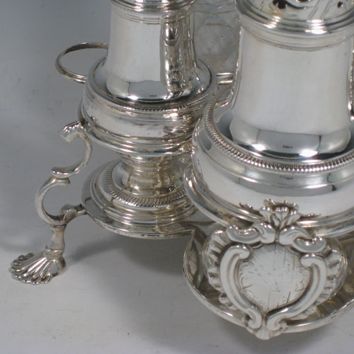 Antique Georgian sterling silver and hand-cut crystal five-bottle Warwick style cruet set, having a stand with scroll work holders, a cast and twisted loop handle, a cast applied cartouche and sitting on four cast shell feet. With two smaller baluster style pepper pots, a larger caster, and two crystal shakers with silver tops. Made by Jabez Daniel and James Mince of London in 1767. The dimensions of this fine hand-made silver cruet set are width of stand 19 cms (7.5 inches), height of stand 23 cms (9 inches), and weight of silver approx. 770g (24.8 troy ounces). Please note that the silver tops on the crystal bottles are unmarked, and the stand is crested.   