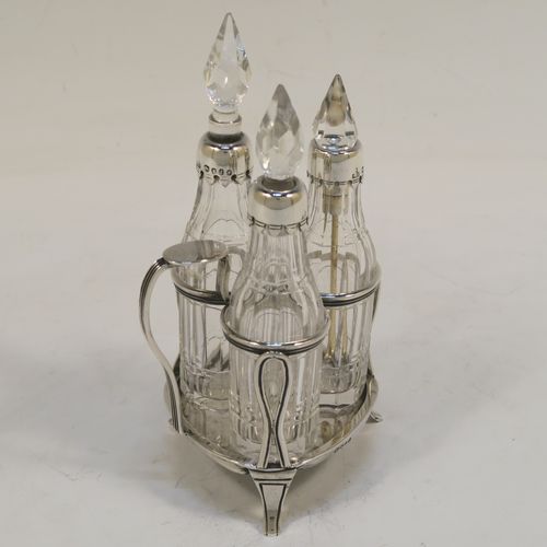 A small but very pretty Antique Victorian Sterling Silver and crystal bottle cruet set, having a plain frame with applied reeded borders, a matching side-handle with thumb-piece, three original crystal bottles with stoppers and silver collars, two for oil and vinegar and the third for mustard or chili sauce with its original gold-gilt spoon, all sitting on a base with three flange feet. This beautiful cruet set was made by Francis Boone Thomas of London in 1873. The dimensions of this fine hand-made antique silver cruet set are height 13.5 cms (5.3 inches), length 7.5 cms (3 inches), and width 6 cms (2.3 inches).    