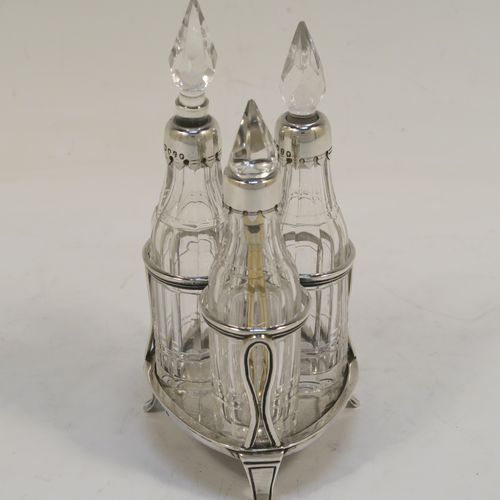 A small but very pretty Antique Victorian Sterling Silver and crystal bottle cruet set, having a plain frame with applied reeded borders, a matching side-handle with thumb-piece, three original crystal bottles with stoppers and silver collars, two for oil and vinegar and the third for mustard or chili sauce with its original gold-gilt spoon, all sitting on a base with three flange feet. This beautiful cruet set was made by Francis Boone Thomas of London in 1873. The dimensions of this fine hand-made antique silver cruet set are height 13.5 cms (5.3 inches), length 7.5 cms (3 inches), and width 6 cms (2.3 inches).    