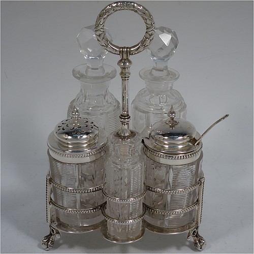 A very pretty Antique Victorian Sterling Silver table cruet set, consisting of two crystal bottles with original stoppers for oil and vinegar, a pepper shaker with crystal body and pierced silver lid, a salt/mustard pot with crystal body and silver hinged lid and condiment spoon, and a smaller bottle with silver serving spoon for a piquant sauce. All sitting in their original galleried frame with bead-edged borders, a cast laurel-leaf ring handle, and four cast claw and ball feet. Made by Martin Hall and Co., of Sheffield in 1868. The dimensions of this fine antique silver cruet set are height 15.5 cms (6 inches), and width 10 cms (4 inches).    