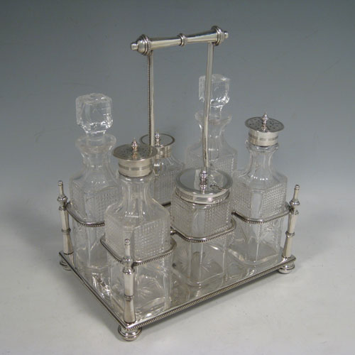    Antique Victorian sterling silver and hand-cut crystal cruet set, having six bottles with reeded mounts, sitting in a rectangular frame with bead edges, on four cushion feet. The frame was made by Walker and Hall of Sheffield in 1900, and the bottles by Bewlay & Co. of Birmingham between 1897 and 1900. Height of frame 22 cms (8.75 inches), length 18 cms (7 inches), width 13 cms (5 inches). Weight of stand approx. 729g (23.5 troy ounces).