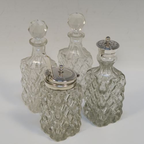 A handsome Antique Victorian Silver Plated and hand-cut crystal cruet set, having four crystal bottles with original stoppers and silver mounts, consisting of an oil and vinegar, a mustard pot spoon, and a pepper shaker, all sitting in a square galleried frame with a wire-work looped handle, and sitting on four cast ball feet. This original antique silver-plated cruet set was ca. 1870. The dimensions of this fine hand-made antique silver-plated cruet set are height of frame 19 cms (7.5 inches), and 11.5 cms (4.5 inches) square.   