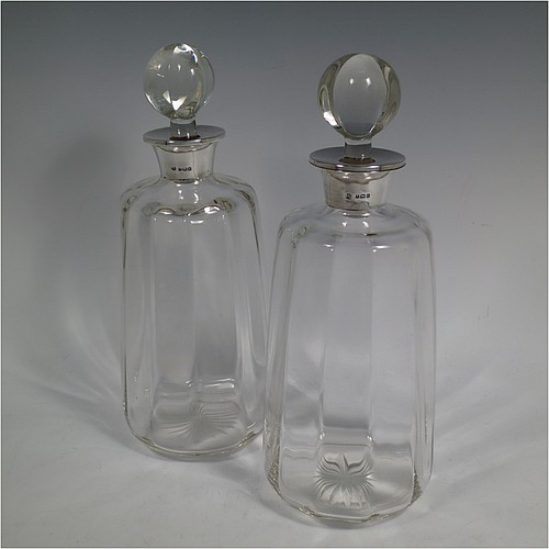 A pair of Antique Sterling Silver and cut-crystal decanters, having plain panelled bodies, plain round silver necks, with original hand-cut lobed stoppers, and all sitting on star-cut flat bases. Made by William Hutton and Sons Ltd., of Birmingham in 1912. The dimensions of this fine pair of antique silver and crystal decanters are height 27 cms (10.75 inches), and diameter at bases 10 cms (4 inches).