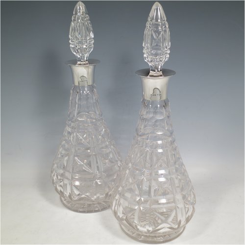 A Sterling Silver and hand-cut crystal pair of decanters, having tear-drop bodies and tapering sides, with hand-cut geometrical decoration, silver collars and lips, and original stoppers. Made by Mappin & Webb of London in 1938. The dimensions of these fine hand-made silver and crystal decanters are height 32 cms (12.5 inches), and diameter 12 cms (4.75 inches).   