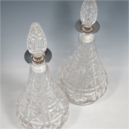 A Sterling Silver and hand-cut crystal pair of decanters, having tear-drop bodies and tapering sides, with hand-cut geometrical decoration, silver collars and lips, and original stoppers. Made by Mappin & Webb of London in 1938. The dimensions of these fine hand-made silver and crystal decanters are height 32 cms (12.5 inches), and diameter 12 cms (4.75 inches).   