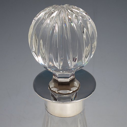 A Sterling Silver and hand-cut crystal decanter, having a round bellied body with tapering sides, hand-cut hobnail and diamond decoration, a silver collar with lip, an original fluted stopper, and sitting on a flat star-cut base. Made by Garrard & Co., of Birmingham in 1971. The dimensions of this fine silver and crystal decanter are height 28 cms (11 inches), and diameter at base 17 cms (6.75 inches).   