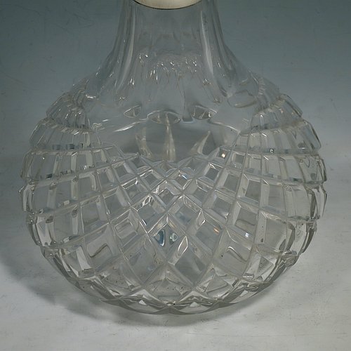 A Sterling Silver and hand-cut crystal decanter, having a round bellied body with tapering sides, hand-cut hobnail and diamond decoration, a silver collar with lip, an original fluted stopper, and sitting on a flat star-cut base. Made by Garrard & Co., of Birmingham in 1971. The dimensions of this fine silver and crystal decanter are height 28 cms (11 inches), and diameter at base 17 cms (6.75 inches).   