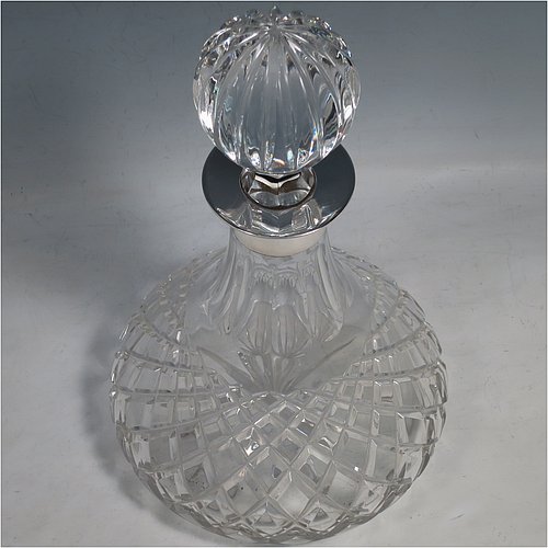 A Sterling Silver and hand-cut crystal decanter, having a round bellied body with tapering sides, hand-cut hobnail and diamond decoration, a silver collar with lip, an original fluted stopper, and sitting on a flat star-cut base. Made by Garrard & Co., of Birmingham in 1971. The dimensions of this fine silver and crystal decanter are height 28 cms (11 inches), and diameter at base 17 cms (6.75 inches).   