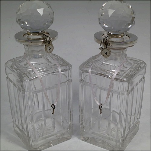 A very handsome pair of Sterling Silver and hand-cut crystal decanters with collar locking mechanisms, having square cross-section bodies with straight sides, hand-cut fluted and reeded decoration, silver collars with lockable clasps, padlocks, and keys, together with their original faceted stoppers. Made by William Gardener Groves  of London in 1931. The dimensions of these fine hand-made silver and crystal lockable decanters are height 23 cms (9 inches), and width 8 cms (3.25 inches) square.   