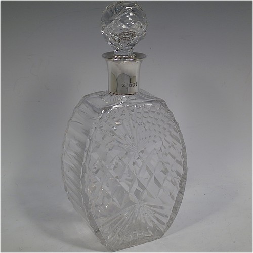 A very unusually designed Sterling Silver and hand-cut crystal decanter, having a main oval body at front and back with hobnail and star-burst cut, and with tapering sides having stepped decoration, a plain silver collar, an original hand-cut stopper, and sitting on a flat base with a matching star-cut. Made by Mappin and Webb of Sheffield in 1956. The dimensions of this fine hand-made silver and crystal decanter are height 25.5 cms (10 inches), width 12 cms (4.75 inches), and depth at base 7 cms (2.75 inches).    