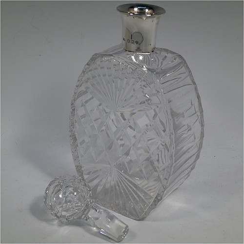 A very unusually designed Sterling Silver and hand-cut crystal decanter, having a main oval body at front and back with hobnail and star-burst cut, and with tapering sides having stepped decoration, a plain silver collar, an original hand-cut stopper, and sitting on a flat base with a matching star-cut. Made by Mappin and Webb of Sheffield in 1956. The dimensions of this fine hand-made silver and crystal decanter are height 25.5 cms (10 inches), width 12 cms (4.75 inches), and depth at base 7 cms (2.75 inches).    